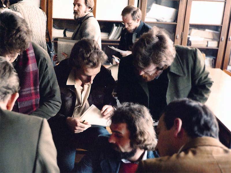 A group of men looking at papers in a library.